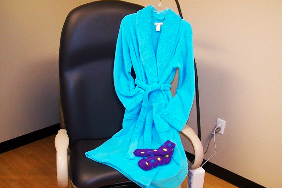A chair with a blue bathrobe and purple socks.